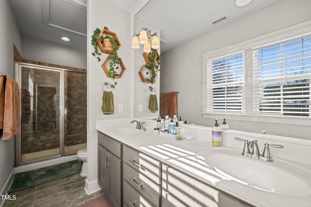 bathroom with toilet, a stall shower, visible vents, and a sink