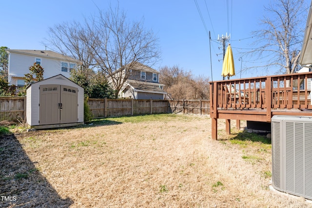 view of yard featuring a storage shed, central AC unit, a fenced backyard, an outbuilding, and a wooden deck