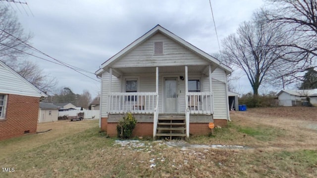 bungalow with covered porch and a front lawn