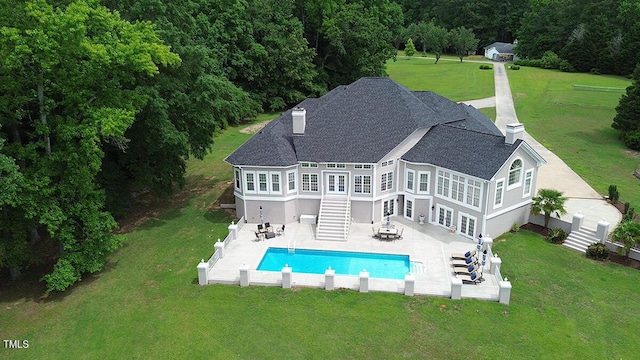 back of house with a fenced in pool, a lawn, and a patio area