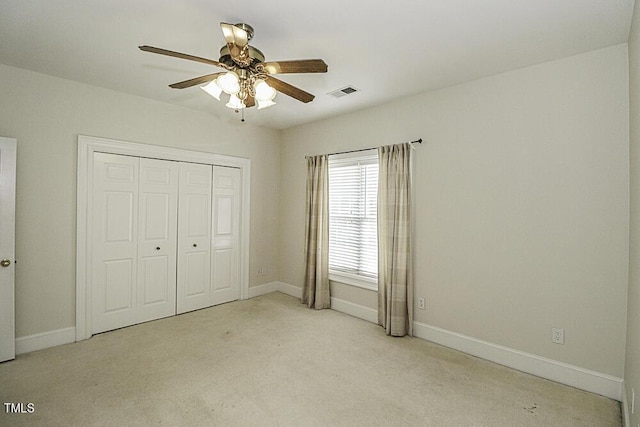 unfurnished bedroom with light carpet, ceiling fan, and a closet