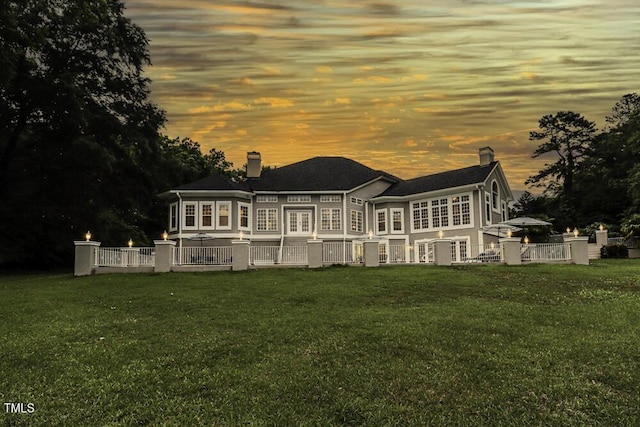 back house at dusk with a lawn