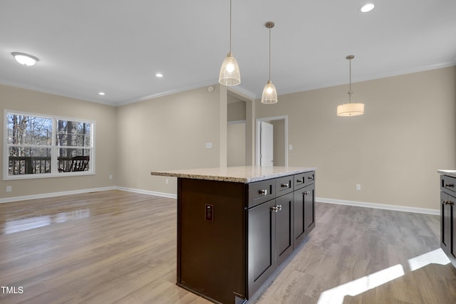 kitchen with dark brown cabinets, crown molding, hanging light fixtures, and light hardwood / wood-style flooring