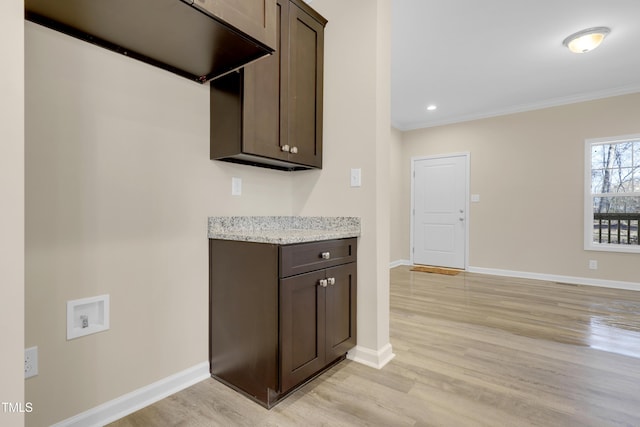 kitchen featuring light wood-type flooring, dark brown cabinets, crown molding, and light stone countertops