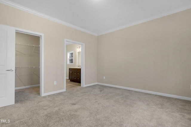 unfurnished bedroom featuring a closet, a spacious closet, connected bathroom, crown molding, and light colored carpet