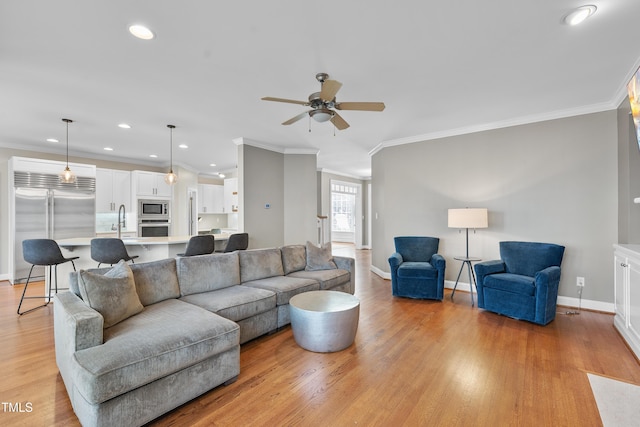 living area featuring baseboards, crown molding, and light wood finished floors