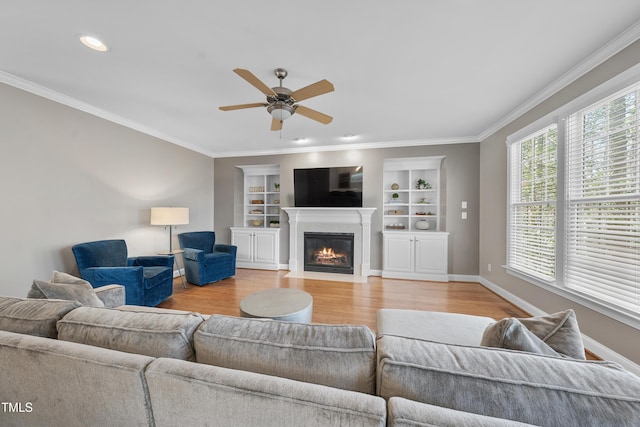 living room with baseboards, a fireplace with flush hearth, ornamental molding, and wood finished floors