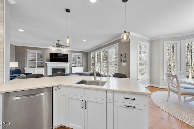 kitchen with open floor plan, stainless steel dishwasher, a sink, and ornamental molding