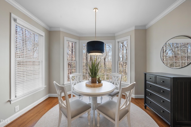 dining area with ornamental molding, baseboards, and wood finished floors