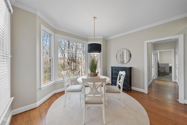 dining space with ornamental molding, baseboards, and wood finished floors