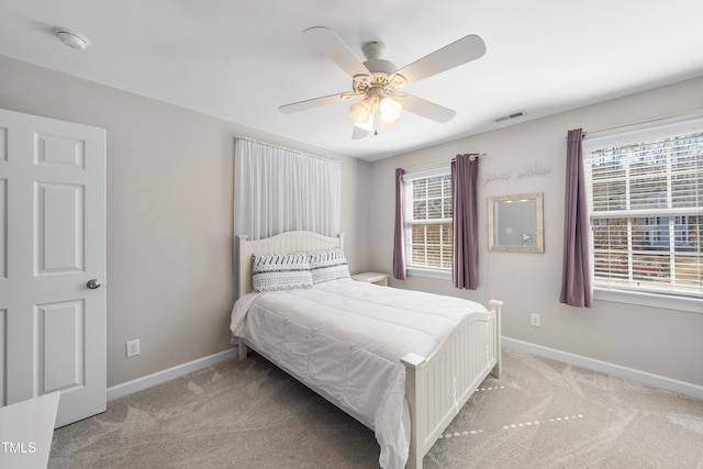 carpeted bedroom featuring baseboards, multiple windows, visible vents, and a ceiling fan