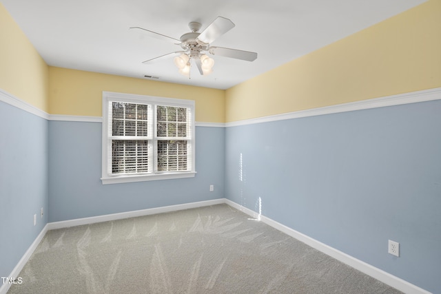 spare room with carpet, visible vents, baseboards, and ceiling fan