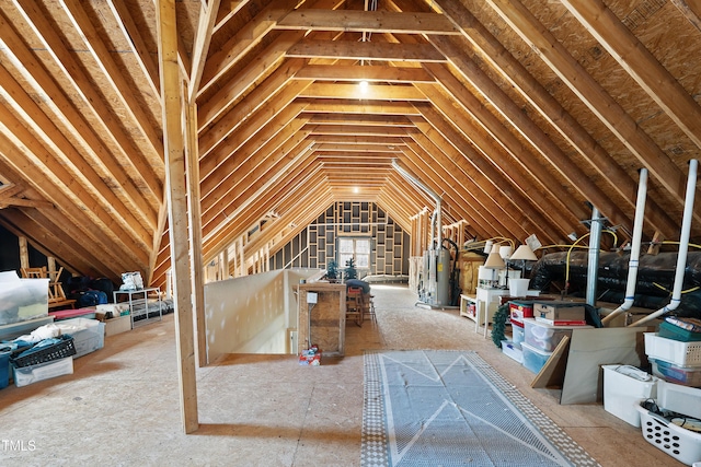 unfinished attic featuring gas water heater and an upstairs landing