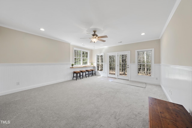 carpeted spare room with a wainscoted wall, a ceiling fan, crown molding, and recessed lighting