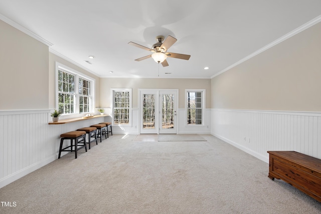 carpeted empty room with a ceiling fan, wainscoting, crown molding, french doors, and recessed lighting