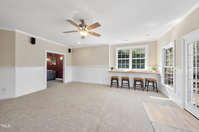 carpeted empty room featuring ornamental molding, recessed lighting, a wainscoted wall, and a ceiling fan