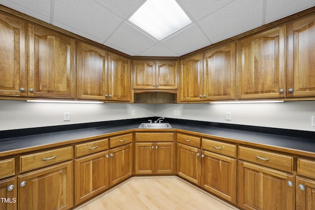 kitchen featuring brown cabinetry, dark countertops, and a sink