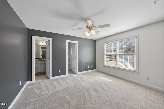 unfurnished bedroom featuring carpet, visible vents, a spacious closet, ensuite bathroom, and baseboards