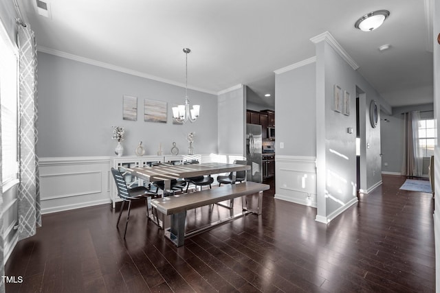 dining room with an inviting chandelier, ornamental molding, and dark hardwood / wood-style floors