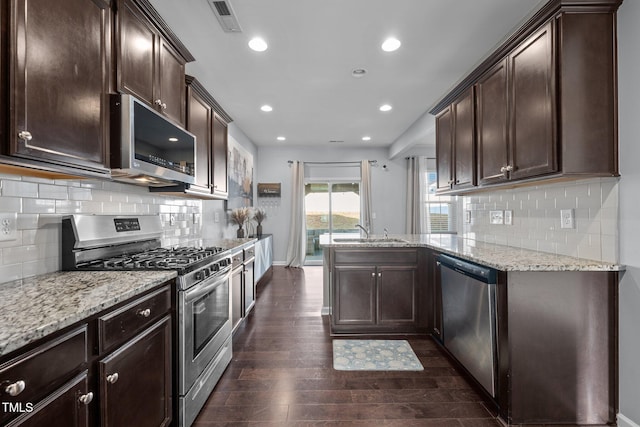 kitchen featuring dark brown cabinetry, light stone countertops, dark hardwood / wood-style floors, and appliances with stainless steel finishes