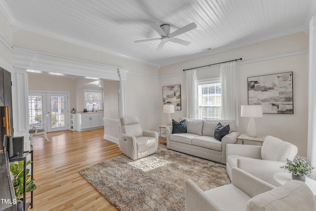 living room featuring french doors, a healthy amount of sunlight, light hardwood / wood-style floors, and ornate columns