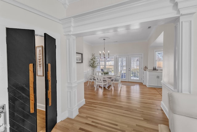 hall with crown molding, an inviting chandelier, light hardwood / wood-style floors, and french doors