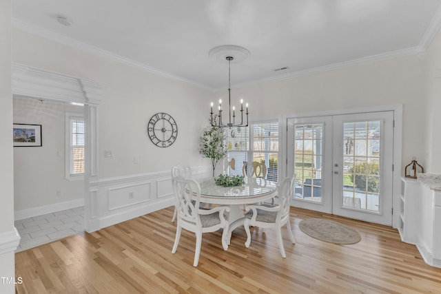 dining space featuring crown molding, light hardwood / wood-style floors, french doors, and a notable chandelier