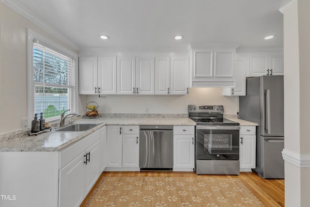 kitchen with sink, wall chimney range hood, light hardwood / wood-style flooring, white cabinetry, and stainless steel appliances