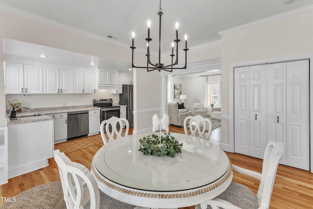 dining room featuring crown molding, sink, light hardwood / wood-style flooring, and a notable chandelier