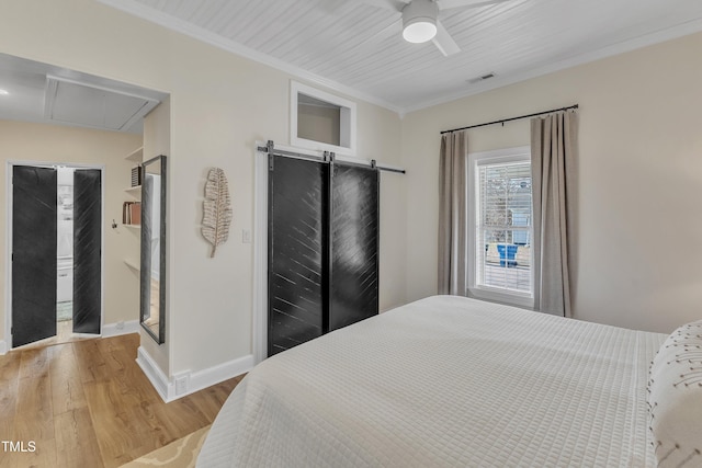 bedroom featuring hardwood / wood-style flooring, ornamental molding, a barn door, and ceiling fan