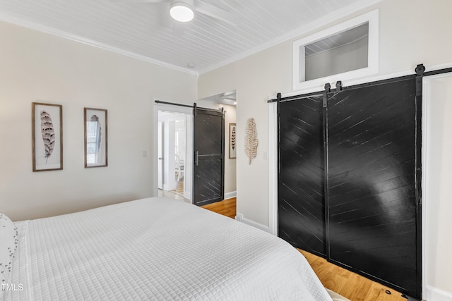 bedroom featuring hardwood / wood-style flooring, ornamental molding, and a barn door