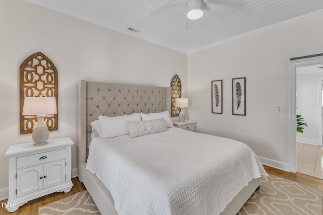 bedroom featuring crown molding, light hardwood / wood-style flooring, and ceiling fan