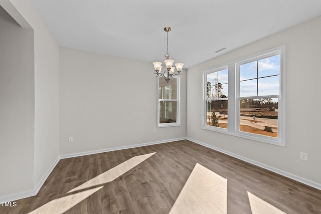 unfurnished dining area with an inviting chandelier and hardwood / wood-style floors