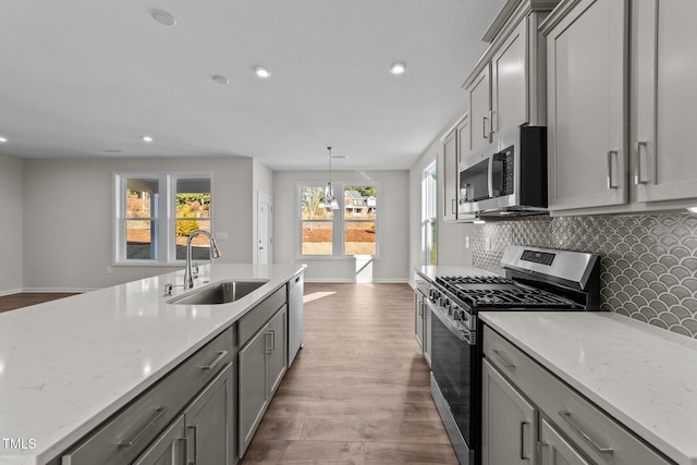 kitchen with pendant lighting, sink, gray cabinets, appliances with stainless steel finishes, and tasteful backsplash