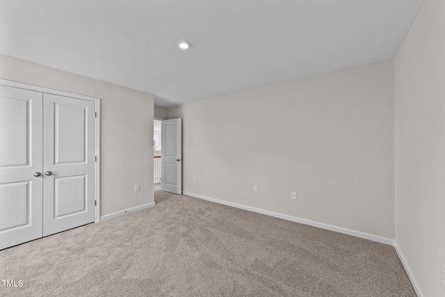 unfurnished bedroom with light colored carpet and a closet