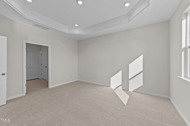 carpeted spare room with a raised ceiling, ornamental molding, and a wealth of natural light