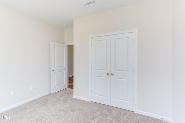 unfurnished bedroom featuring light carpet and a closet