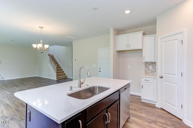 kitchen featuring sink, white cabinetry, hanging light fixtures, stainless steel dishwasher, and a kitchen island with sink