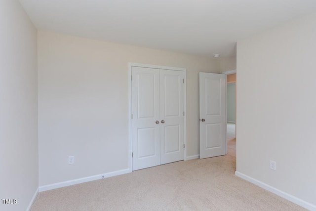 unfurnished bedroom featuring light carpet and a closet