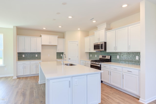 kitchen with a kitchen island with sink, appliances with stainless steel finishes, sink, and white cabinets