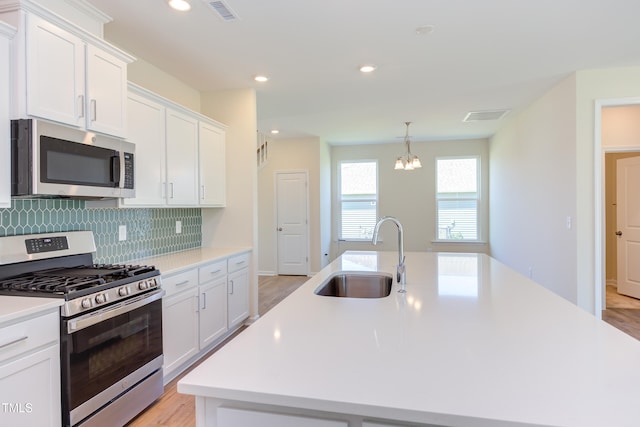 kitchen with a kitchen island with sink, appliances with stainless steel finishes, sink, and white cabinets