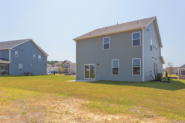 rear view of house featuring central AC unit and a lawn