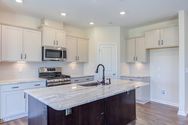 kitchen featuring a kitchen island with sink, sink, stainless steel appliances, and white cabinets