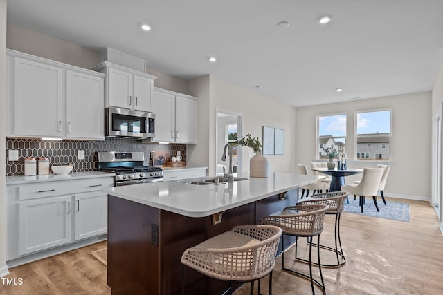 kitchen with a kitchen island with sink, sink, stainless steel appliances, and white cabinets