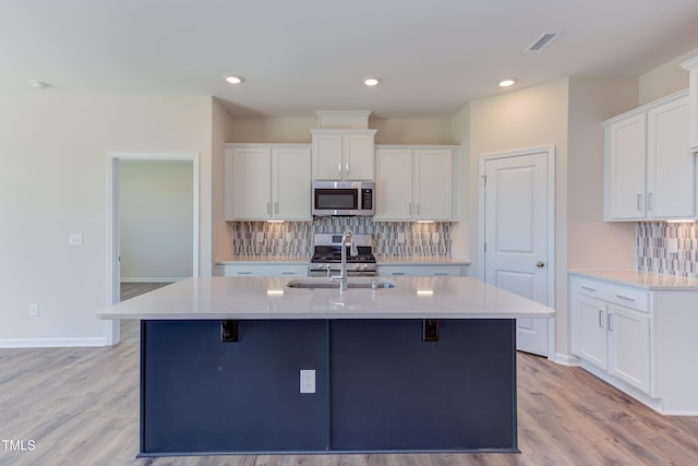 kitchen featuring stainless steel appliances, an island with sink, sink, and white cabinets