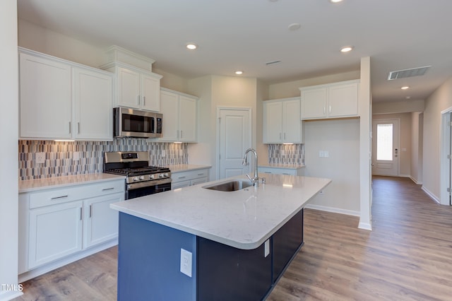 kitchen with white cabinetry, sink, stainless steel appliances, and a center island with sink