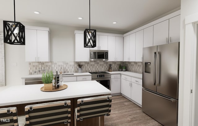 kitchen with stainless steel appliances, hanging light fixtures, light countertops, and white cabinetry