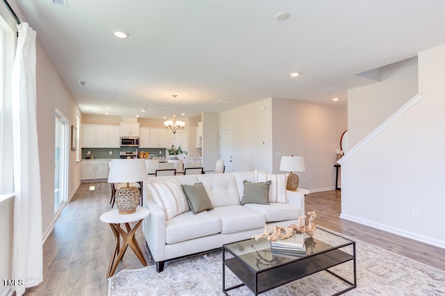 living room featuring light wood-type flooring and a notable chandelier