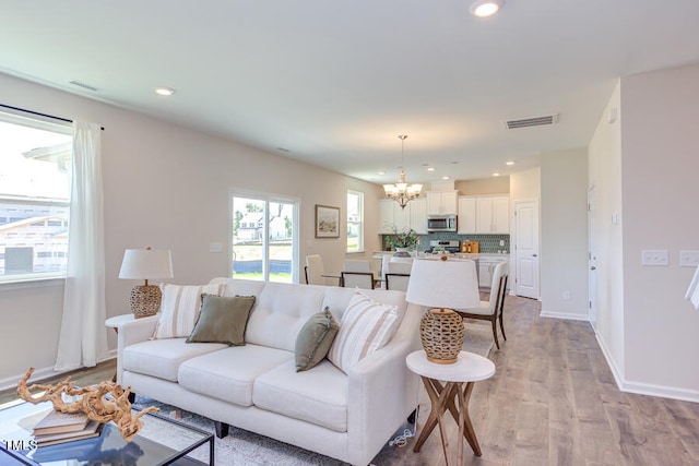 living room with light hardwood / wood-style floors and a notable chandelier