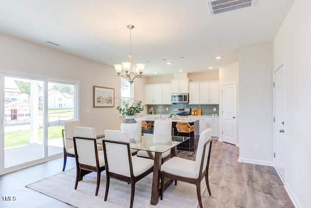 dining room featuring sink, light hardwood / wood-style floors, and a chandelier